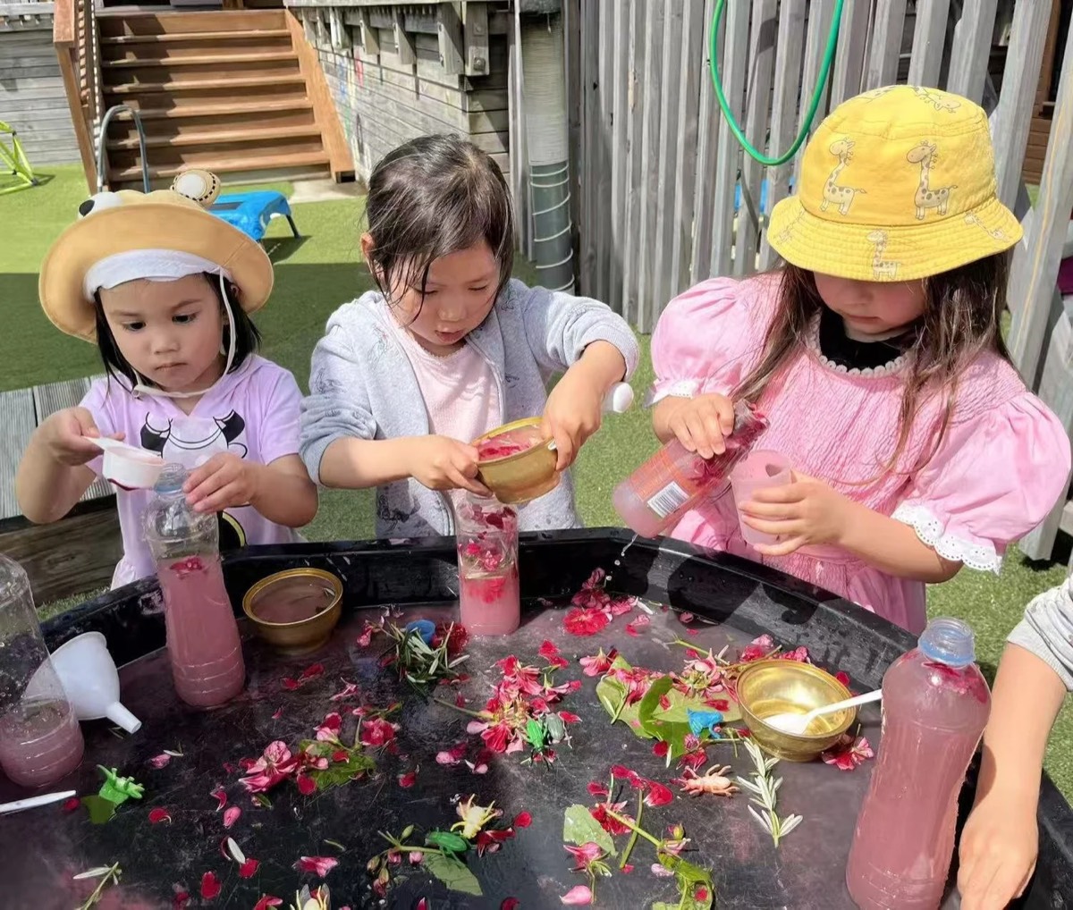 Tamariki exploring a messy-play tray outdoors