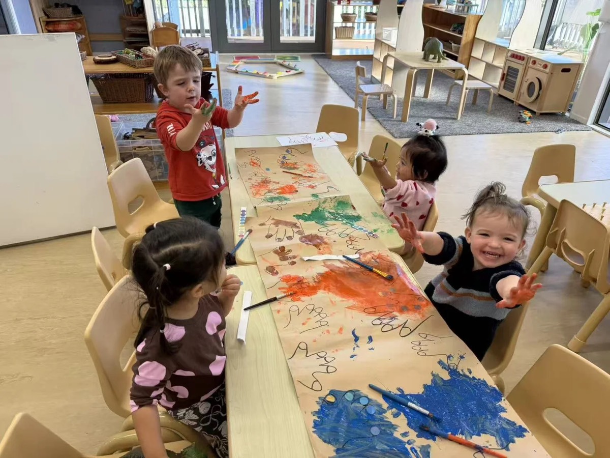 Tamariki painting together on a long sheet of paper